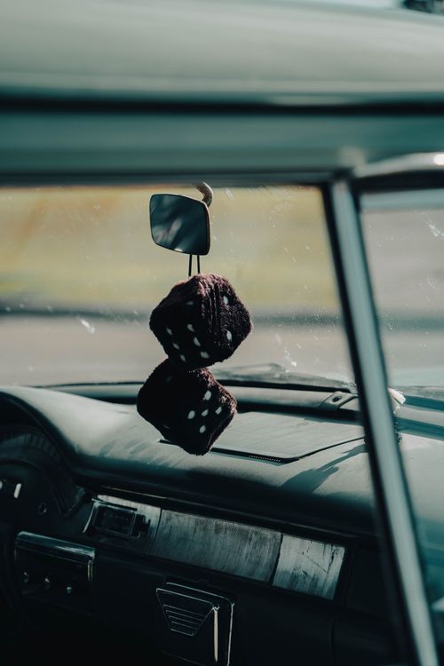 Free Close-up of a classic car interior featuring hanging fuzzy dice on the rear-view mirror. Stock Photo