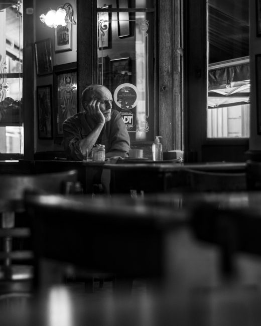 A senior man sitting alone in a classic Buenos Aires bar, deep in thought.