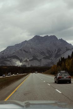 Dramatic view of a highway leading to the Rockies in Canmore, Alberta under an overcast sky.