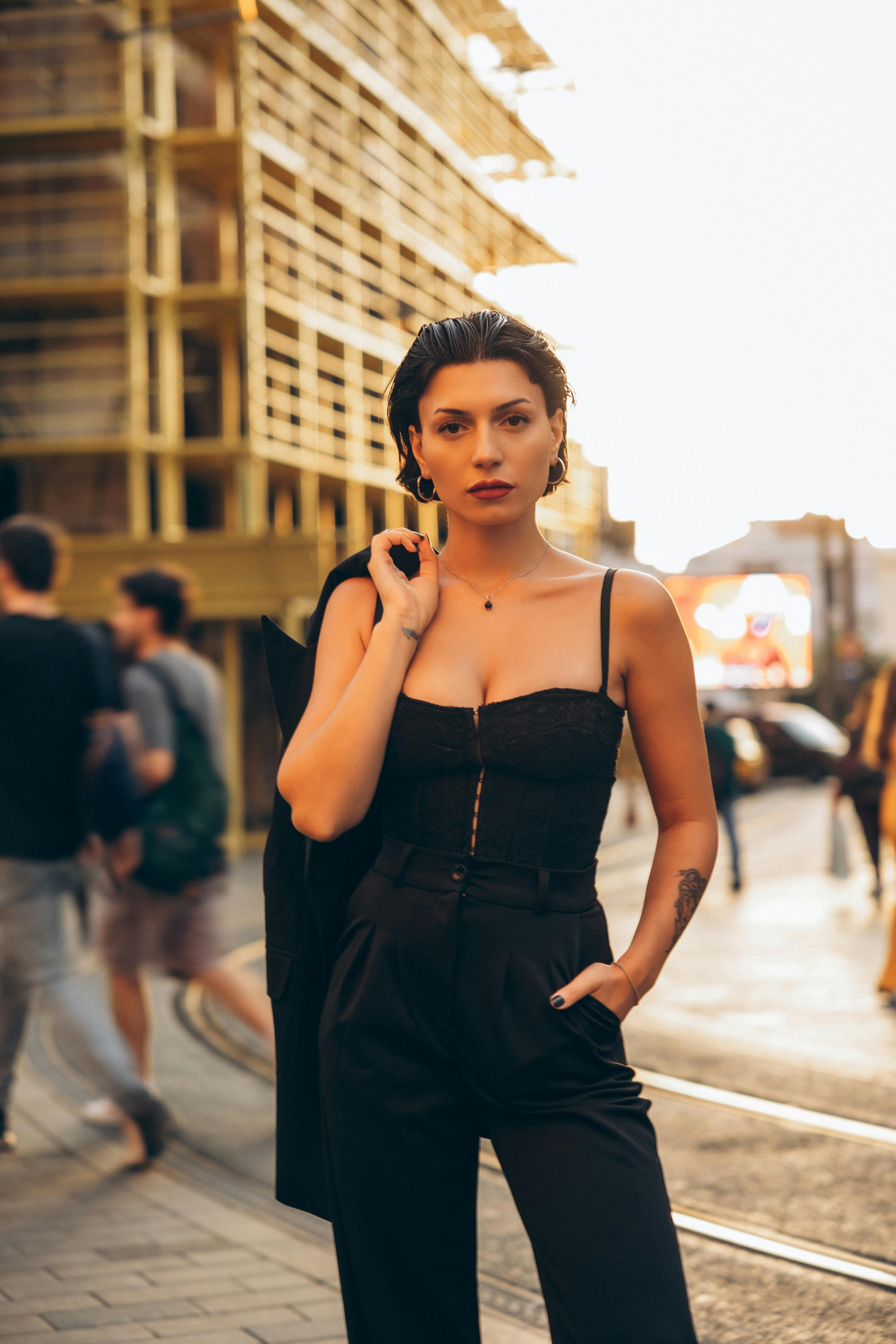 a woman in a black jumpsuit standing on a street