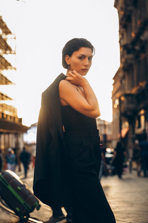 A woman in a black dress standing on a street