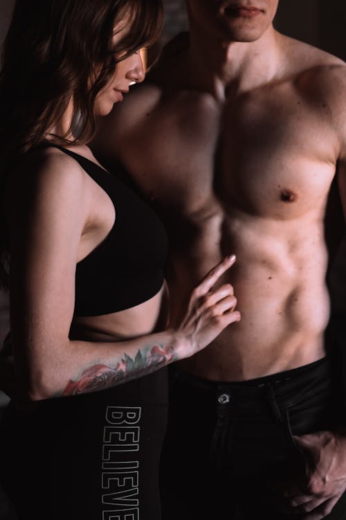 Young Woman Touching the Bare Torso of a Muscular Man