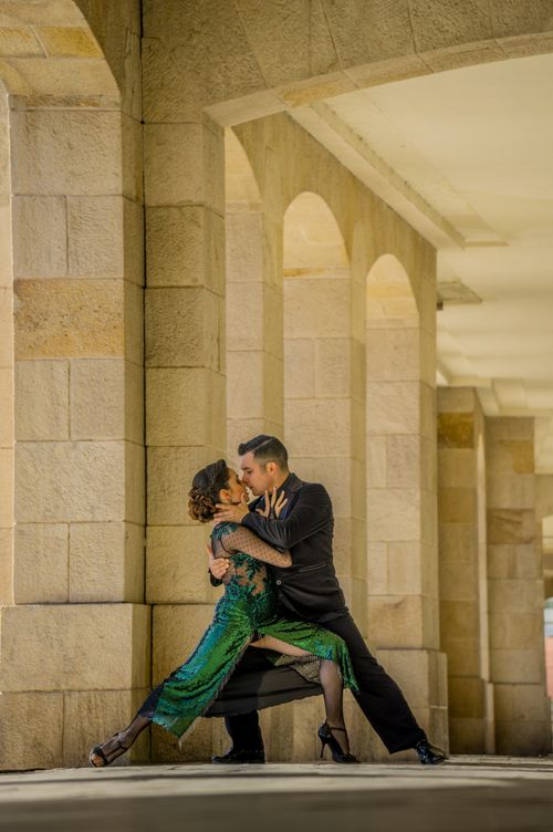 Free An elegant couple dancing passionately under a stone archway, exuding grace and charm. Stock Photo