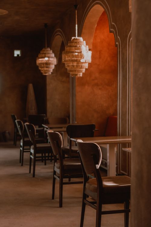 Free Warm, elegant restaurant interior featuring arched walls and chandelier lighting creating a cozy atmosphere. Stock Photo