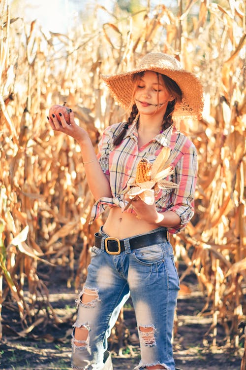 Pretty Woman with Wicker Hat Posing in Corn Field
