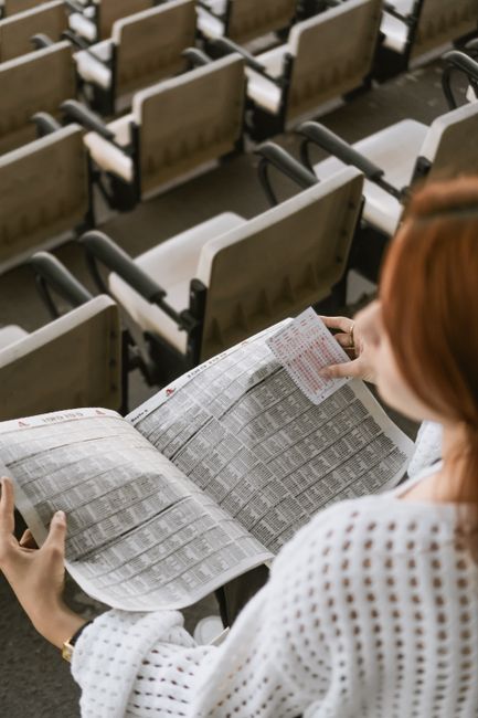 Woman examining paper in an empty lecture hall, viewed from behind.