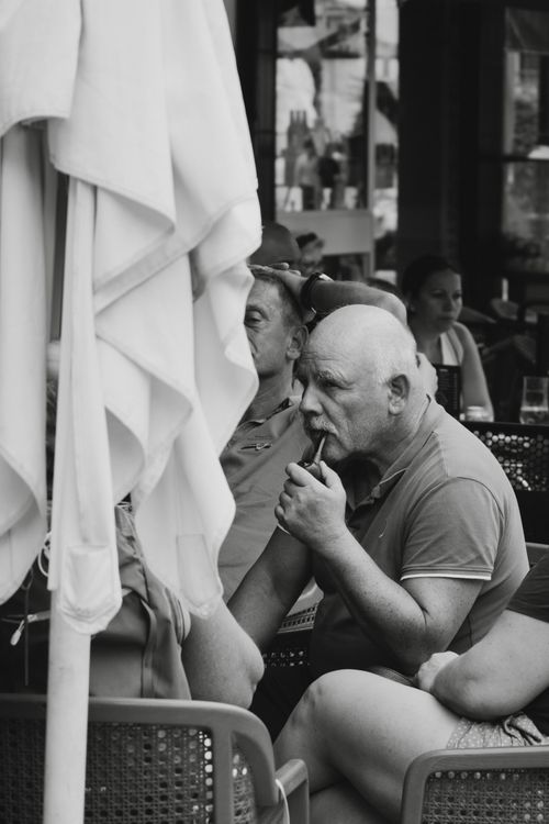 Free A senior man enjoys leisure time at an outdoor café, captured in monochrome. Stock Photo