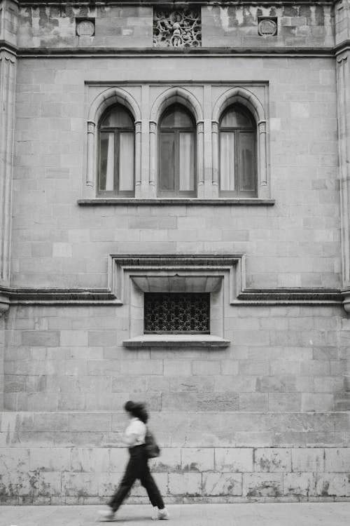 Woman Walking near Building Wall in Black and White