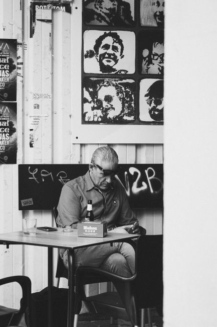 Senior man enjoying leisure time reading in a black and white outdoor caf茅 setting.