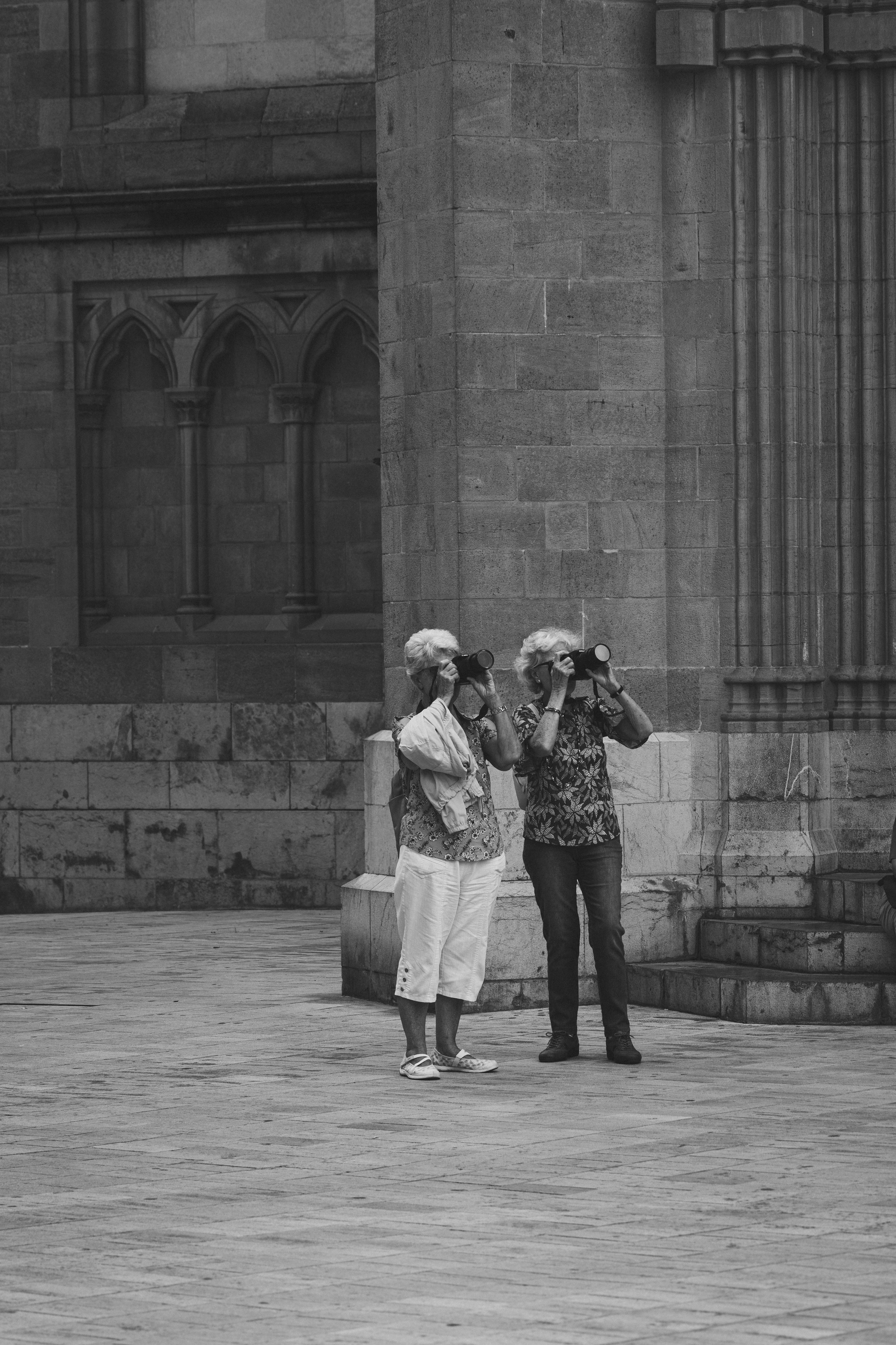 Two senior women photographing Gothic architecture, capturing memories.