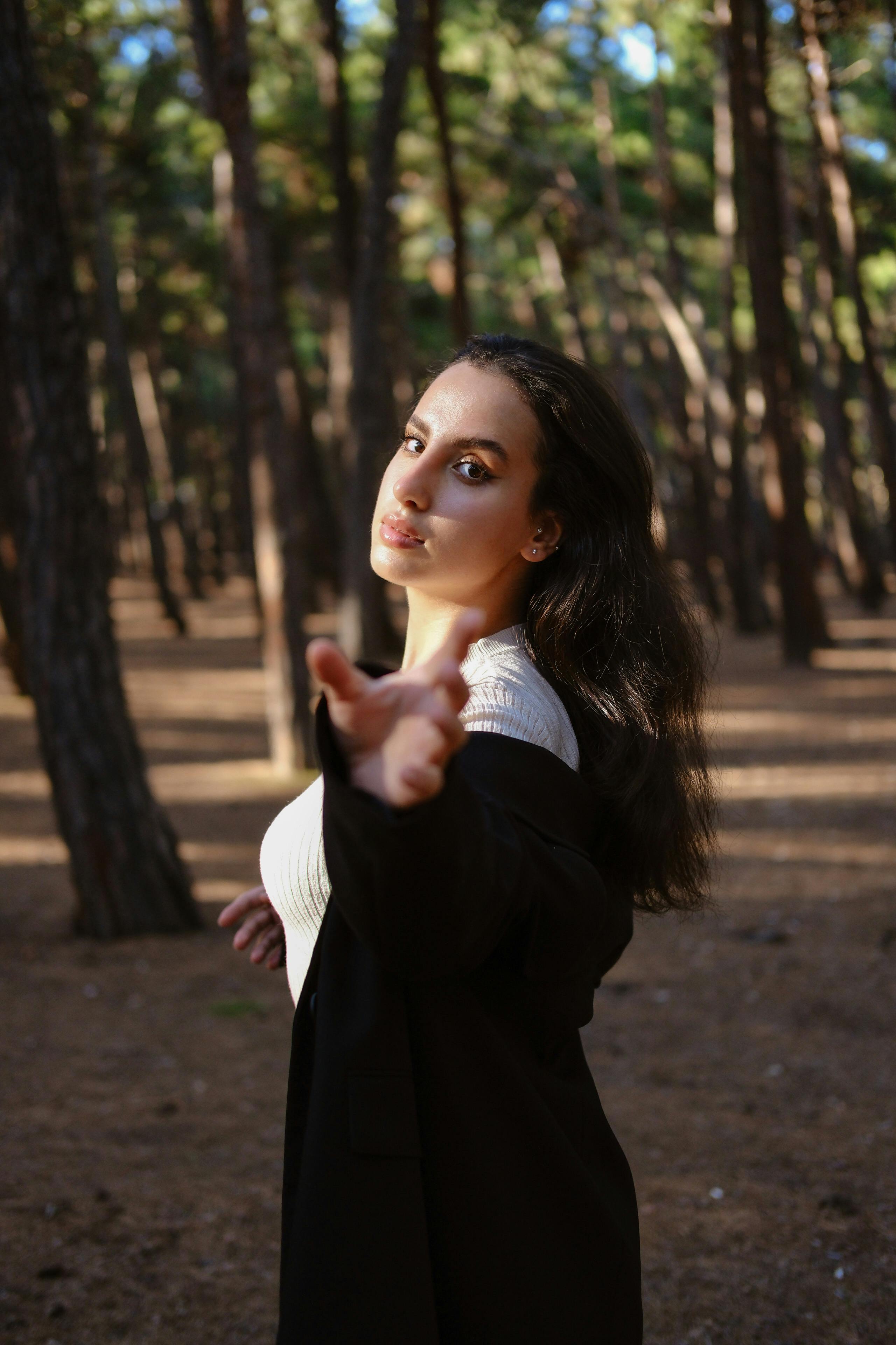 a woman in a forest pointing at something