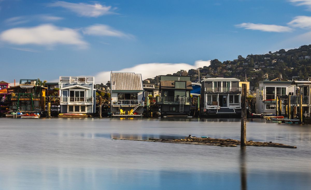 Waterfront homes along a calm inlet with hills rising behind them