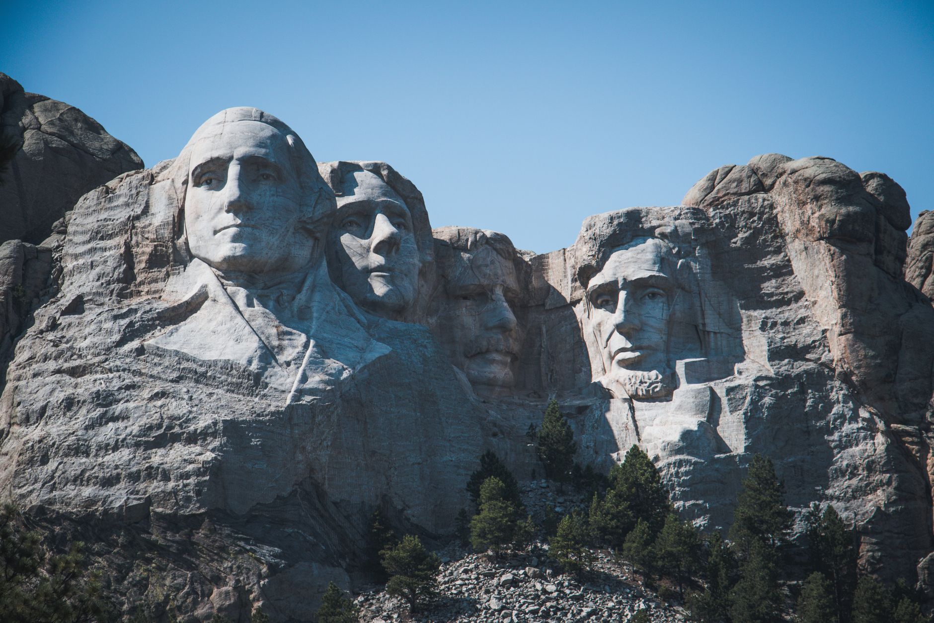 Capture the grandeur of Mount Rushmore, featuring the iconic presidential sculptures set against a clear blue sky.