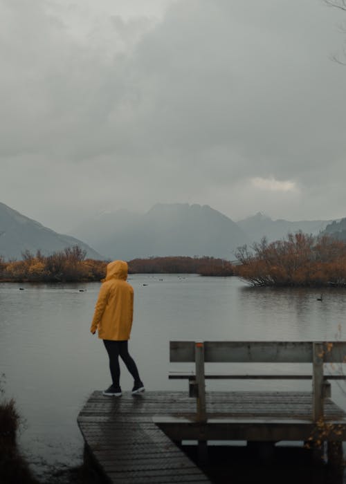 Tourist in a Yellow Raincoat on the Wet Jetty on Lake Wakatipu