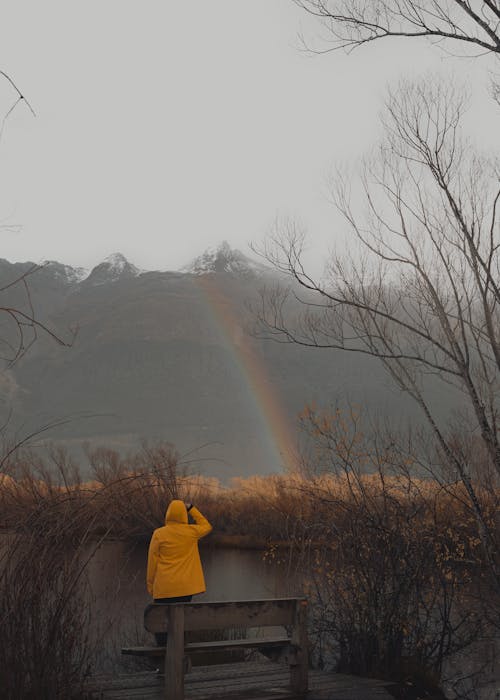 Tourist in a Yellow Raincoat Watching Rainbow on Lake Wakatipu