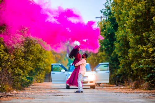 A Couple Posing Outside in Pink Smoke from a Flare 