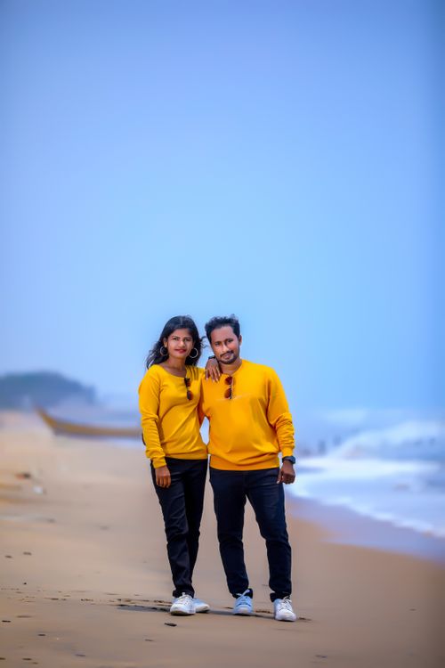 Free Couple in matching yellow sweaters enjoying a peaceful beach walk. Stock Photo