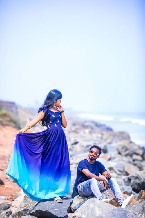 Free Fashionable couple posing on rocky beach, vibrant colors, clear day, unique attire. Stock Photo