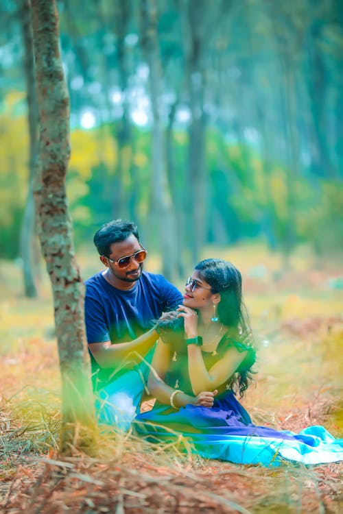 Young Couple Sitting Together in a Forest 