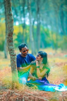 A joyous couple shares a romantic moment outdoors, surrounded by trees and nature. 18815986
