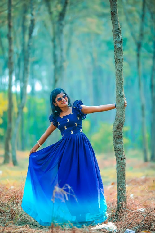 Brunette Woman in Blue Dress Posing by Tree