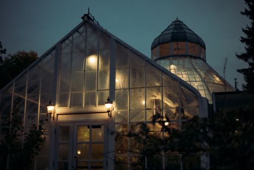 Free A beautifully lit greenhouse at night, showcasing warm glows against a dark sky. Stock Photo