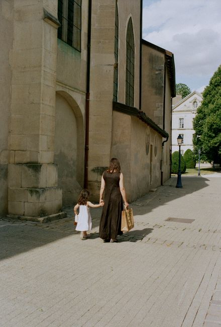 A woman and child walk hand in hand near a church in Nancy, France.