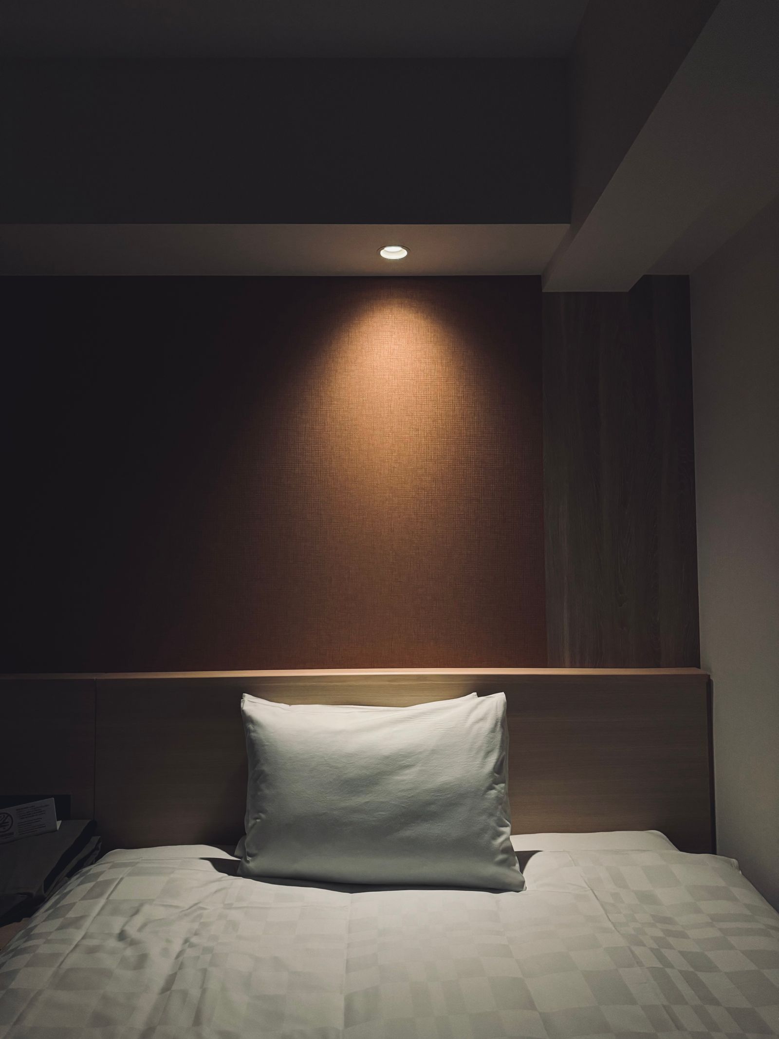 Cozy minimalist hotel room bed in dim lighting