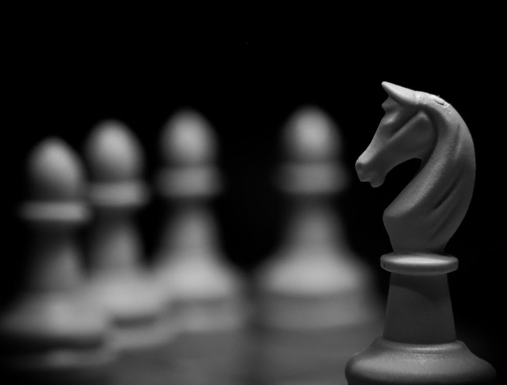 White Knight on Chess Board against Blurry Pieces · Free Stock Photo