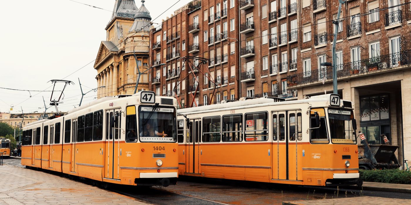 Vintage yellow trams passing by historic buildings in Budapest, Hungary.