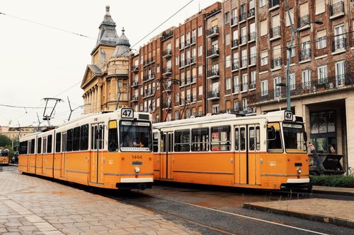 Free Vintage yellow trams passing by historic buildings in Budapest, Hungary. Stock Photo