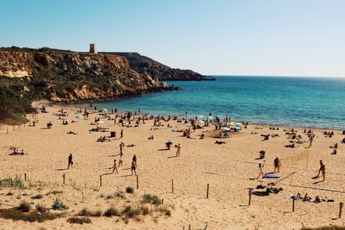 Free Enjoy a summer day at Golden Bay, Malta, with vibrant beachgoers and scenic cliffs. Stock Photo