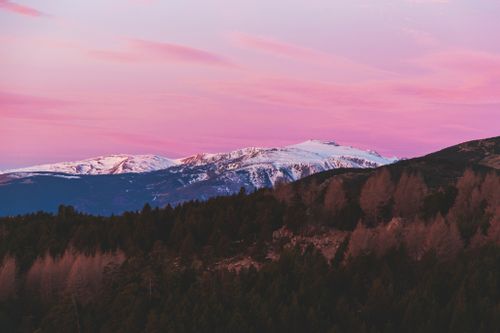 Free A breathtaking landscape of snow-capped mountains under a vibrant pink sky during sunrise. Stock Photo