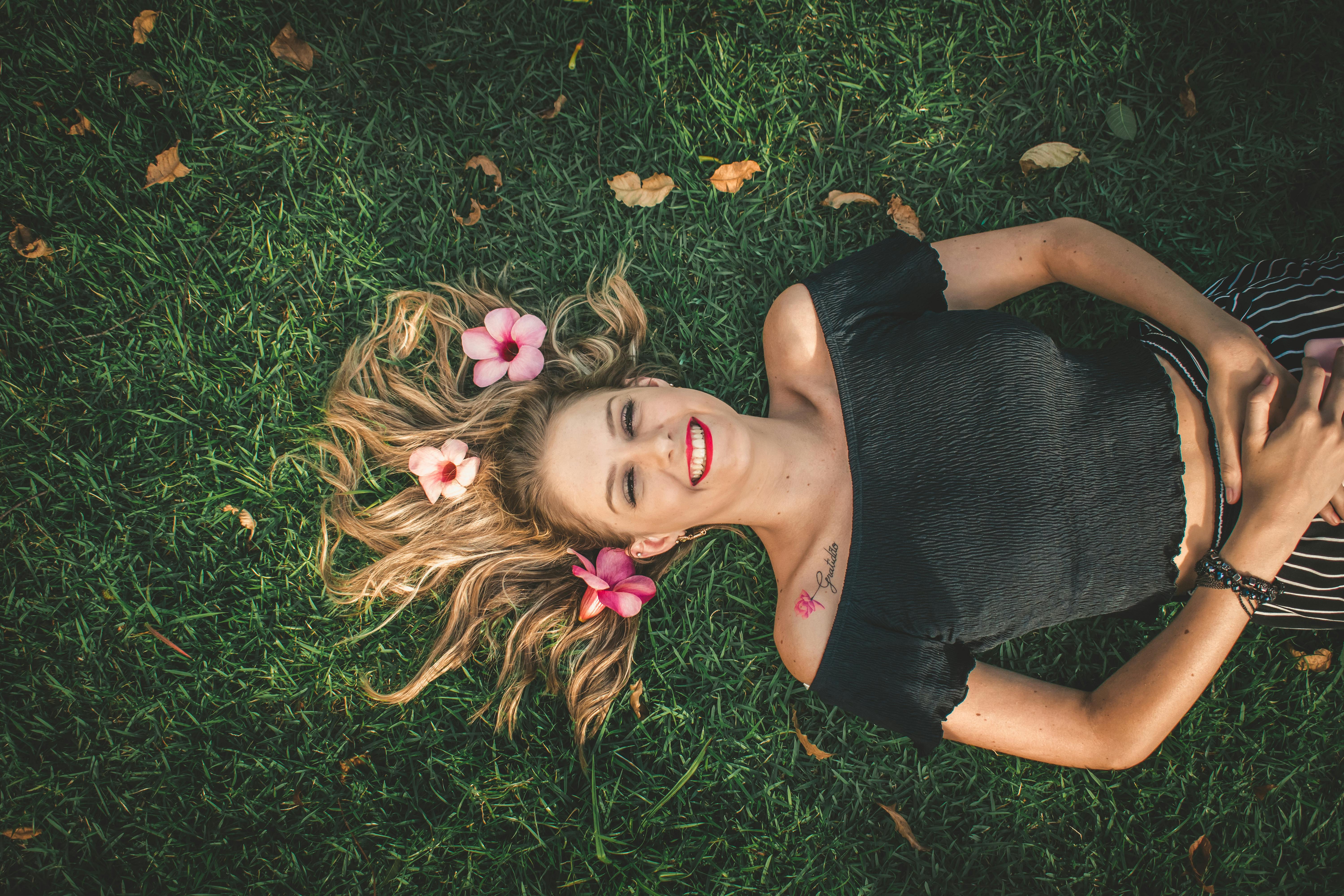 一位女子躺在草地上，微笑着，发间点缀着鲜花，尽显自然之美