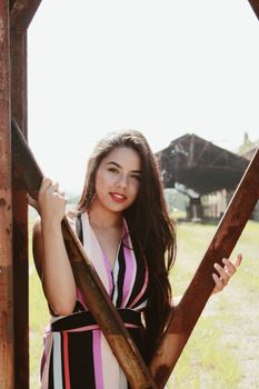 夏日里，一位时尚女士身着充满活力的条纹连衣裙在户外摆姿，散发着自信与时尚气息
