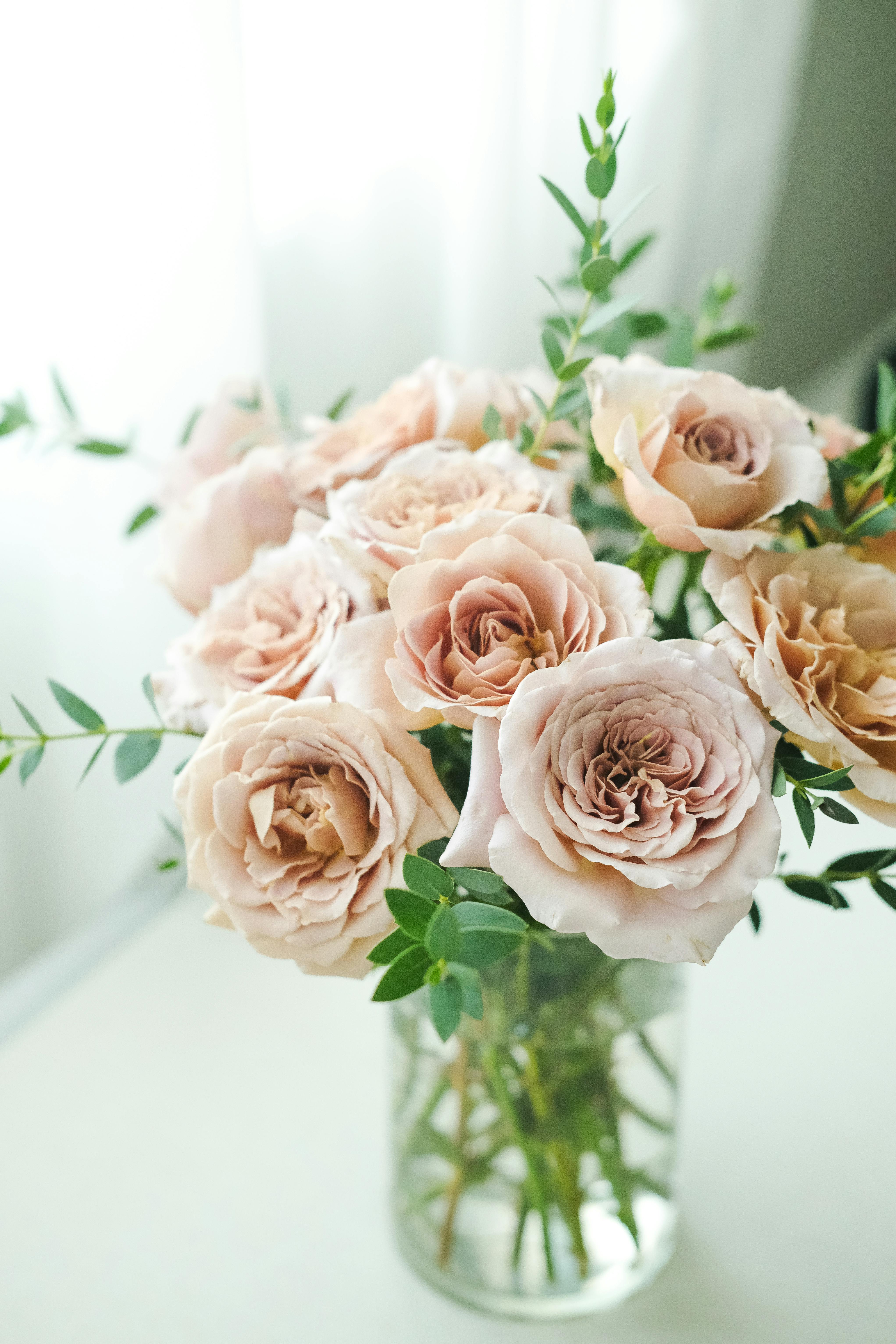 Beautiful pastel roses arranged in a glass vase, perfect for weddings and romantic occasions.