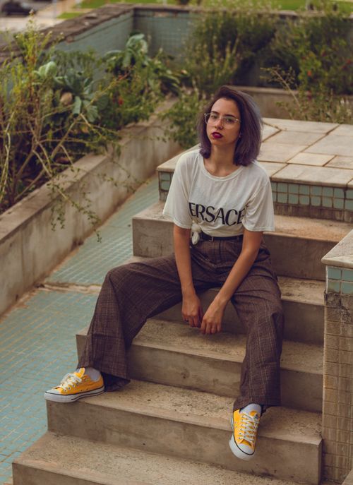 Free Trendy young woman in casual fashion sits outdoors on stairs, showcasing modern style. Stock Photo
