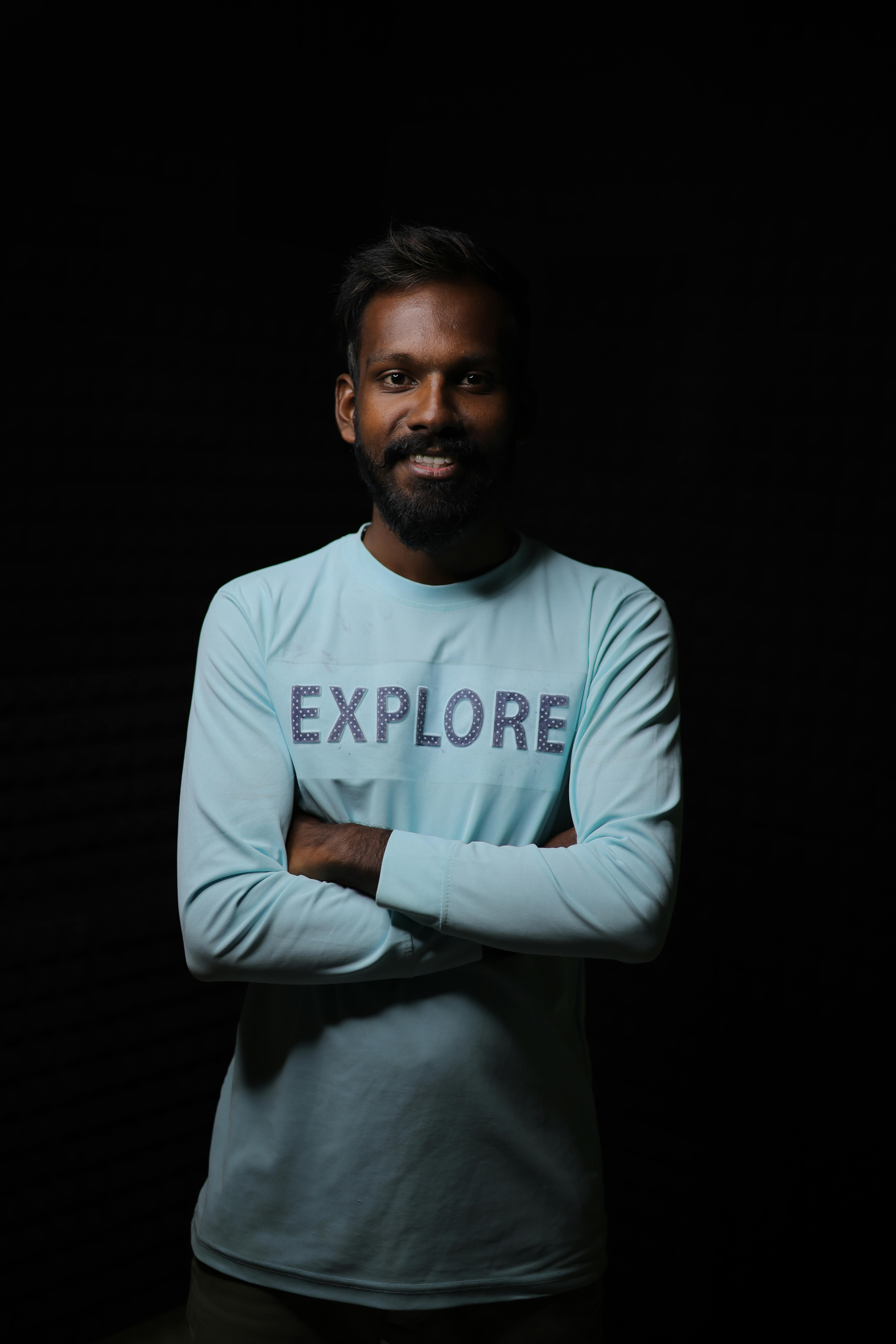 Cheerful man with beard wearing an 'Explore' shirt in a studio setting. Perfect for lifestyle and adventure concepts.