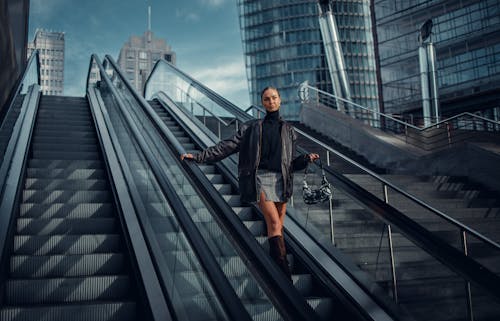 Woman in Denim Skirt, Black Leather and Black High Boots Standing on Escalator
