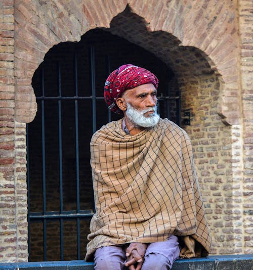 Elderly Man in a Turban Sitting in Front of a Gate