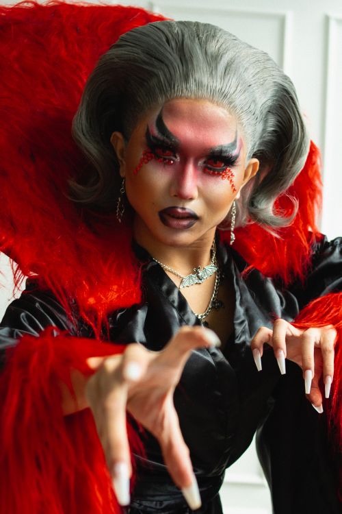 Free Dramatic portrait of a woman in a vampire costume with intense makeup and red accents. Stock Photo