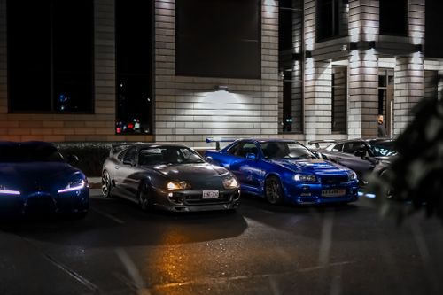Free Line of luxury sports cars parked at night in urban setting, highlighting modern elegance. Stock Photo