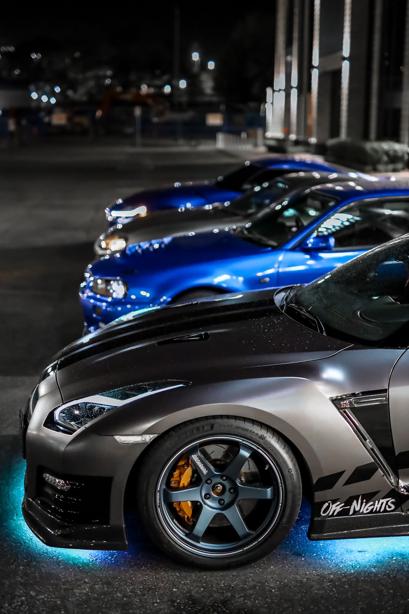 Several sports cars parked together at night