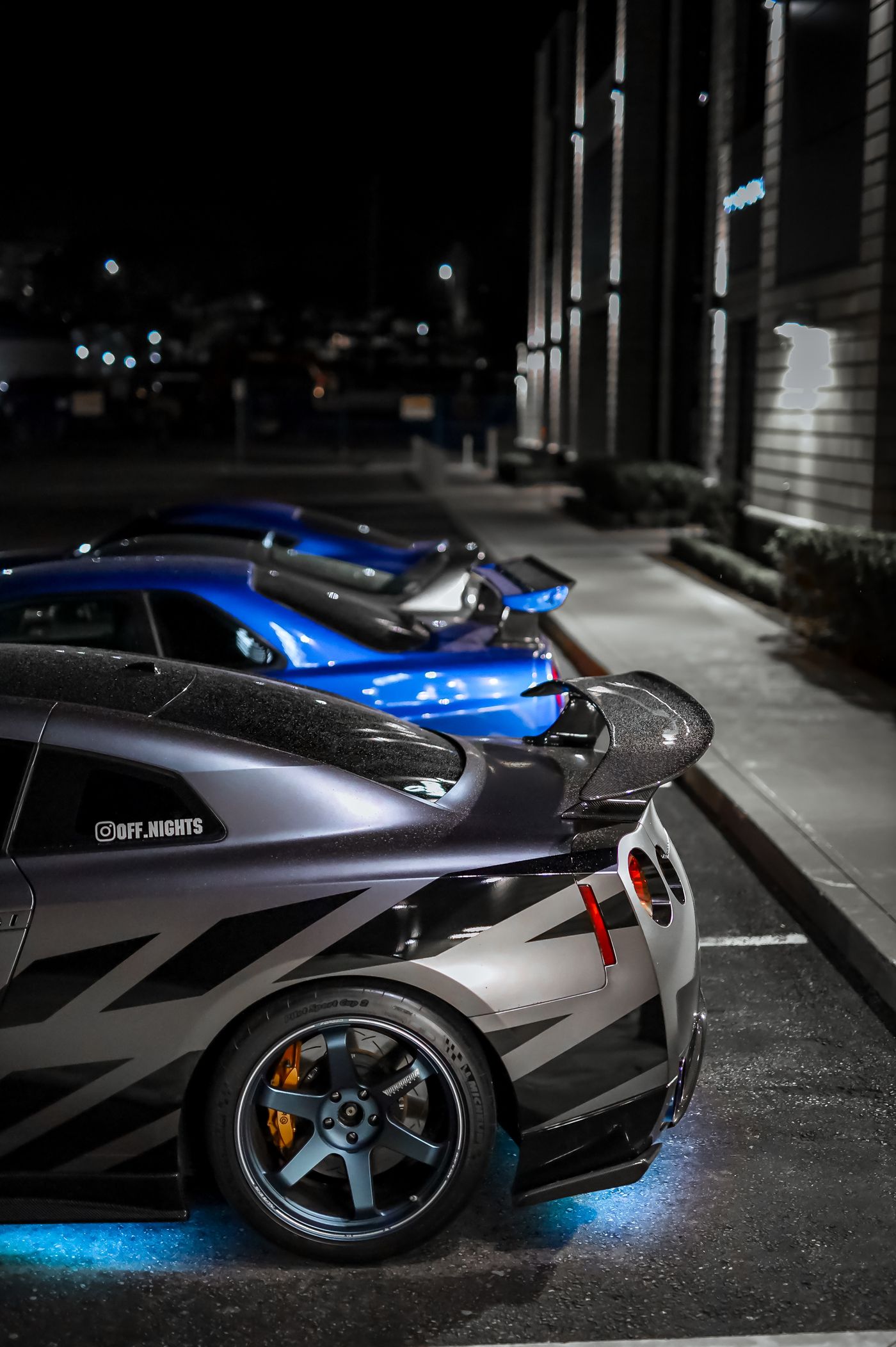 Rear wing and modified Japanese cars at night