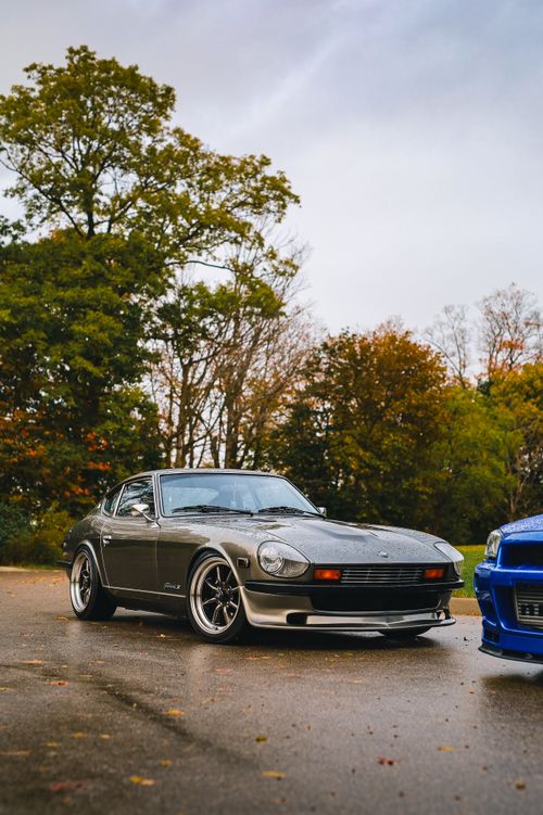 Free Vintage sports car parked in a serene autumn landscape with colorful foliage. Stock Photo