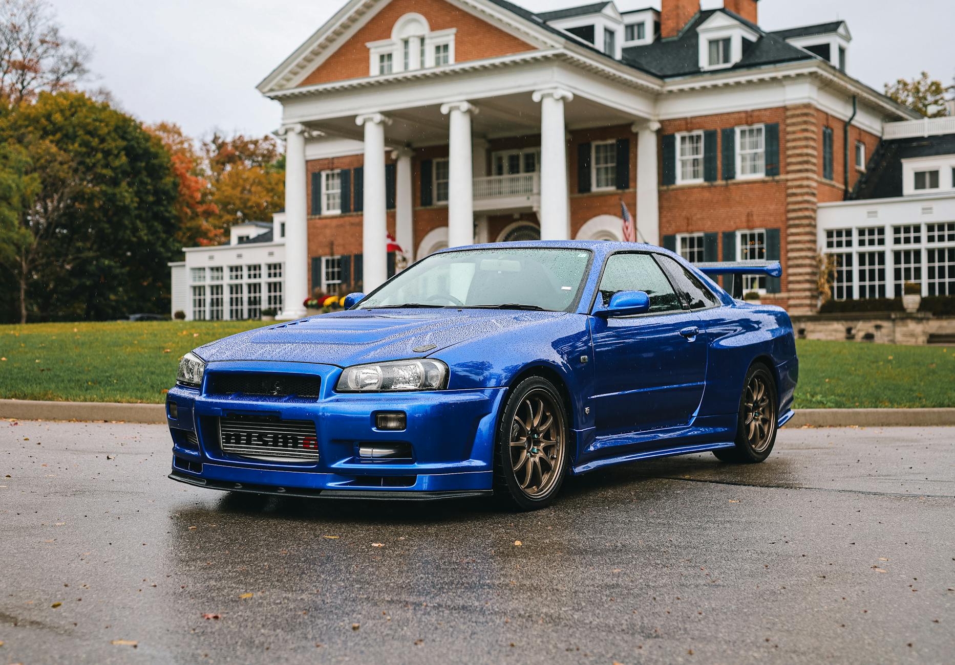 A blue sports car parked outside a grand mansion, showcasing modern automotive design.