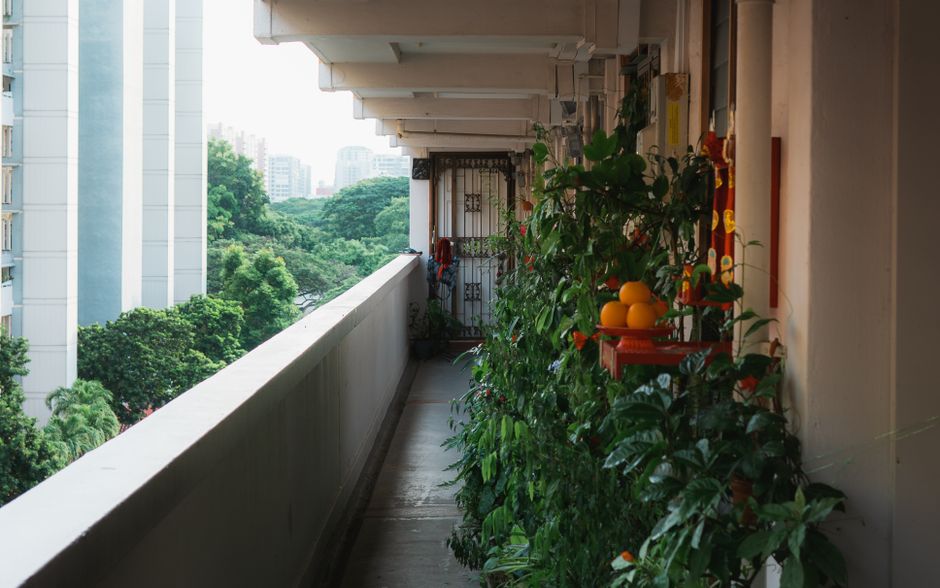 schmaler Stadtbalkon mit Hochbeet, Kräuterkästen und kleinem Tisch in neutralen Tönen