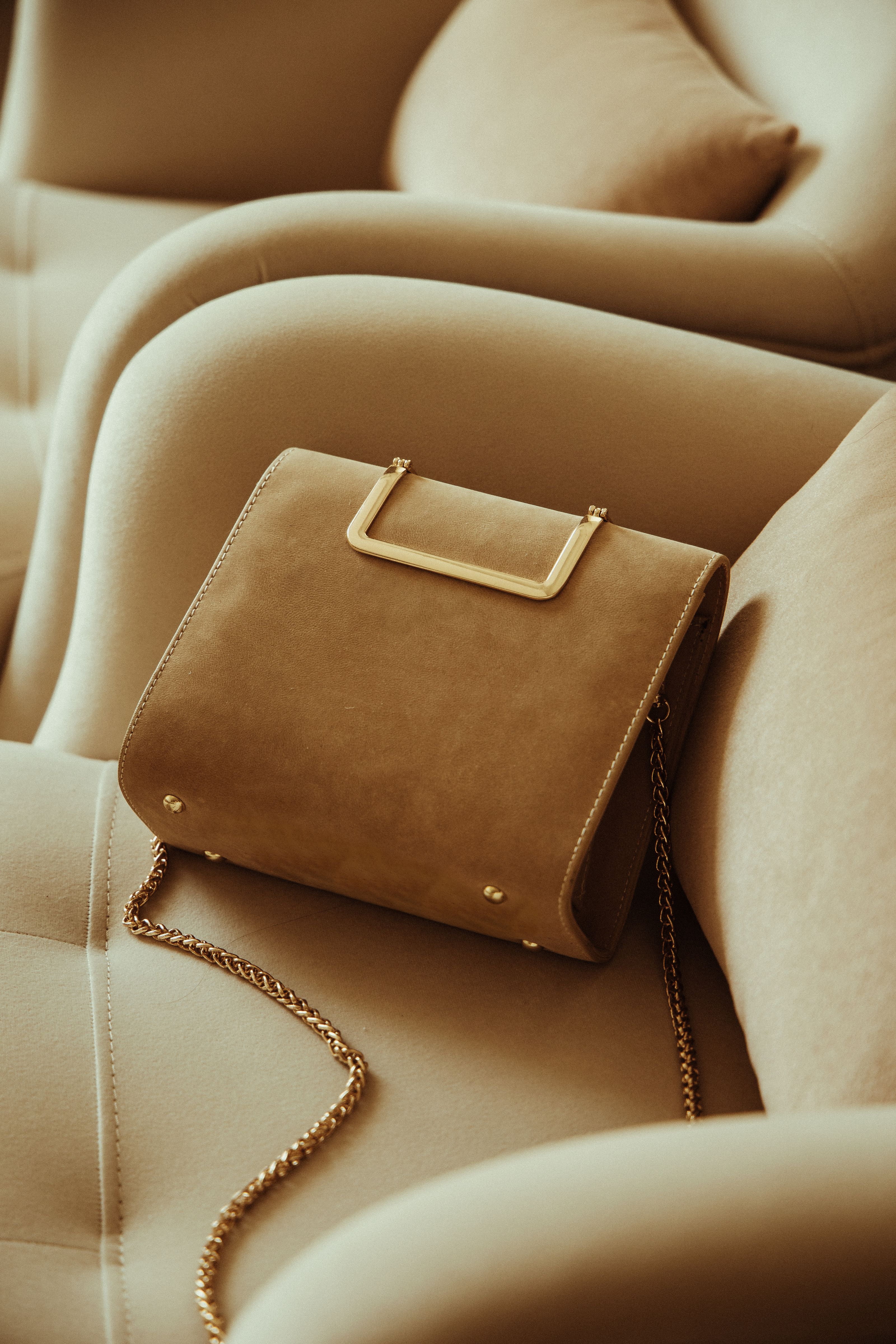 Estilosa bolsa de couro com corrente dourada no banco de um carro.