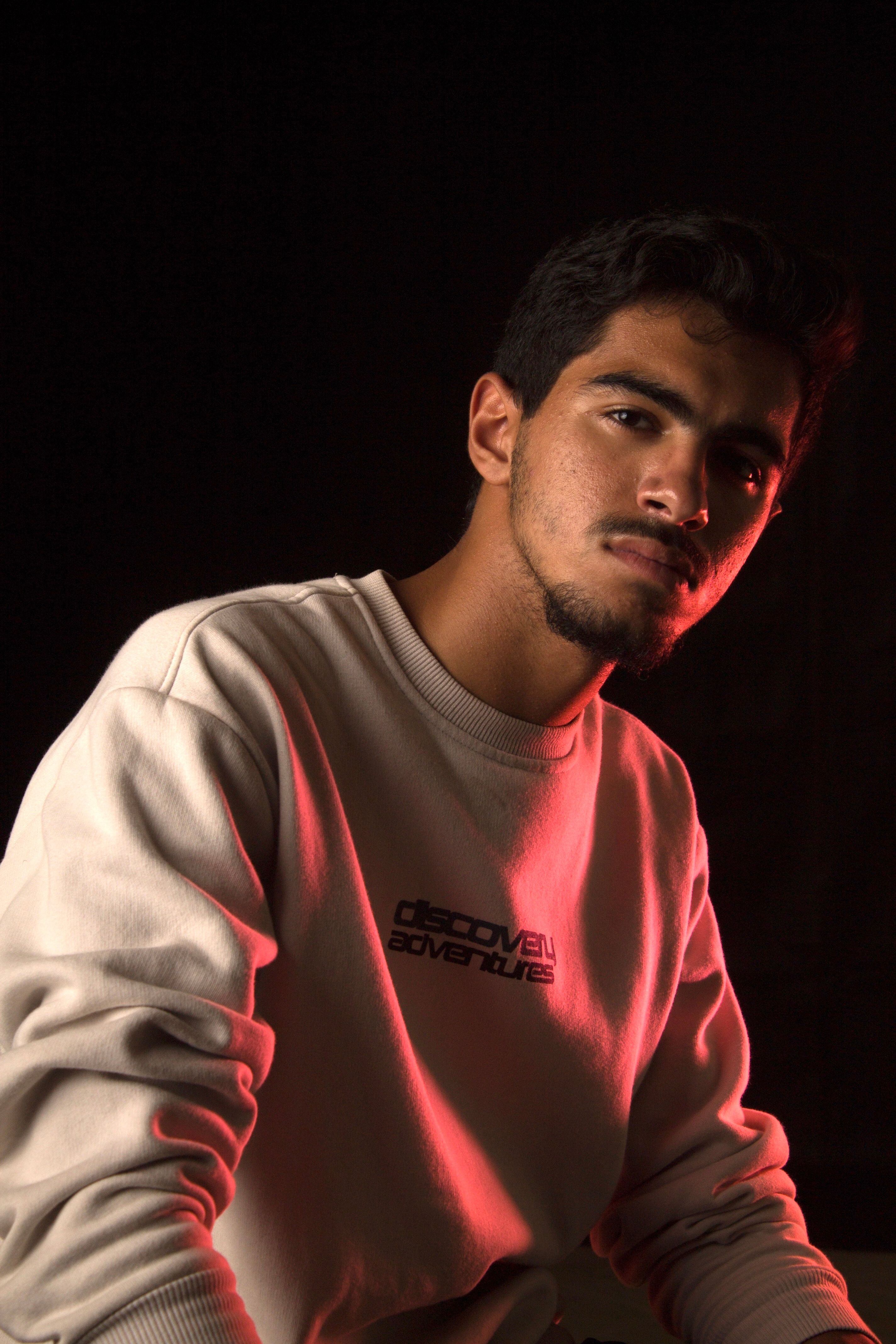 Portrait of a young man in a trendy sweatshirt with red studio lighting.
