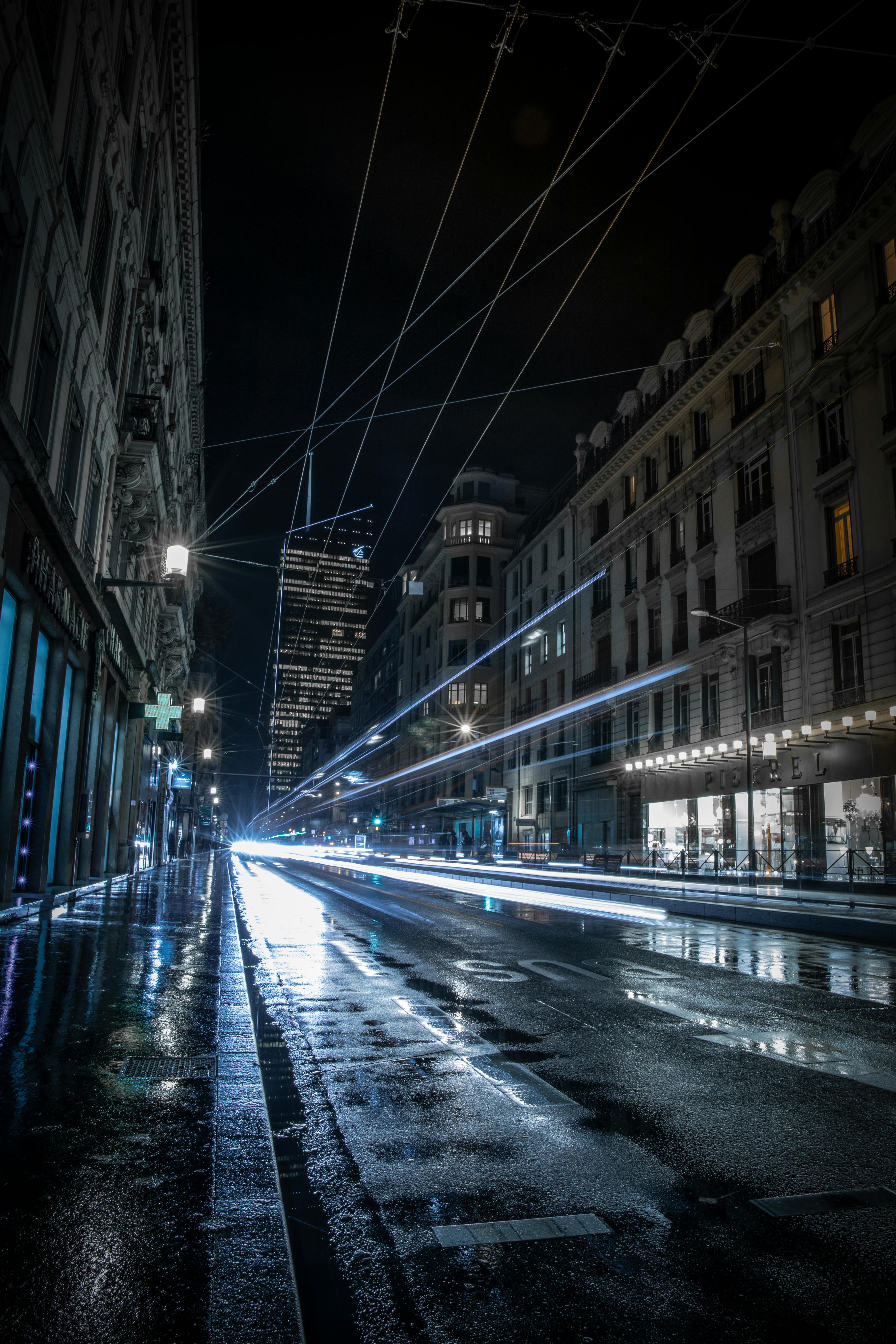 夜晚的城市街道充满活力，灯光长时间照射在潮湿的路面上，留下斑驳的痕迹